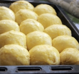 Противень выстелите бумагой. Слепите из теста булочки и положите их на небольшом расстоянии друг от друга, но не впритык. Отнесите противень в теплое место, булочки должны подняться и соединиться бочками.
Разогрейте духовку. В мисочке смешайте желток и сливки и полученной смесью смажьте булочки.