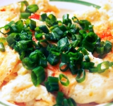 На среднем огне готовьте омлет, пока нижняя часть не поджарится. Омлет будет очень мягким, поэтому при переворачивании, скорее всего, развалится, но это нисколько не отразится на вкусе!
Переверните омлет и готовьте секунд 40. Выложите на тарелку, посыпьте черным перцем и нарезанным зеленым луком. Приятного аппетита!