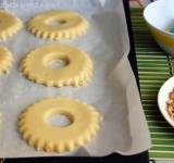 Присыпаем стол мукой и раскатываем тесто толщиной 6-7 мм. Вырезаем круги большой формочкой, а затем в центре делаем отверстие диаметром 2 см. 
 
Выкладываем кольца на противень с пергаментом, а потом кладем их в морозилку на 20 минут. Это важный этап.  
Чистим жареный арахис и измельчаем (можно при помощи скалки).	