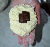 Руки посыпаем муку, формируем из творожного теста лепешку, в центр кладем кусочек шоколада и формируем сырник.