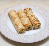 В форме рулета. Блин с двух краев слегка заверните к центу. Затем с одного из оставшегося края начните заворачивать в рулетик.