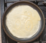 Поставьте на плиту на средний огонь и готовьте около 1 минуты. Низ блина должен стать слегка коричневого цвета.	