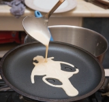 Сначала разогрейте сковороду. Лучше брать специальную блинную сковородку (не с высокими бортами). Смажьте слегка маслом (лучше это сделать специальной кисточкой). Налейте в середину сковороды тесто и распределите его по все поверхности.	