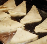 Тесто сложим пополам треугольниками, потом слоенки разложим на противень с фольгой и отправим в прогретую духовку минут на 40.